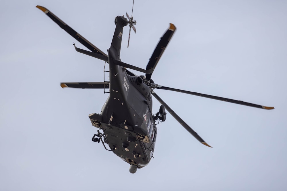 a black helicopter flying through a cloudy sky