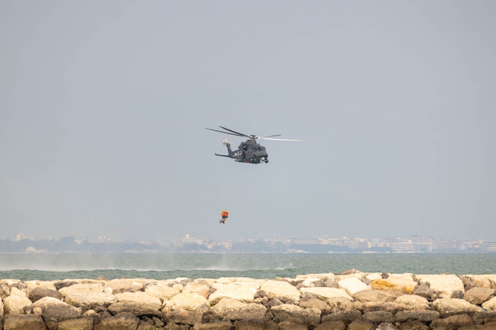 a helicopter flying over the ocean with a person in the air