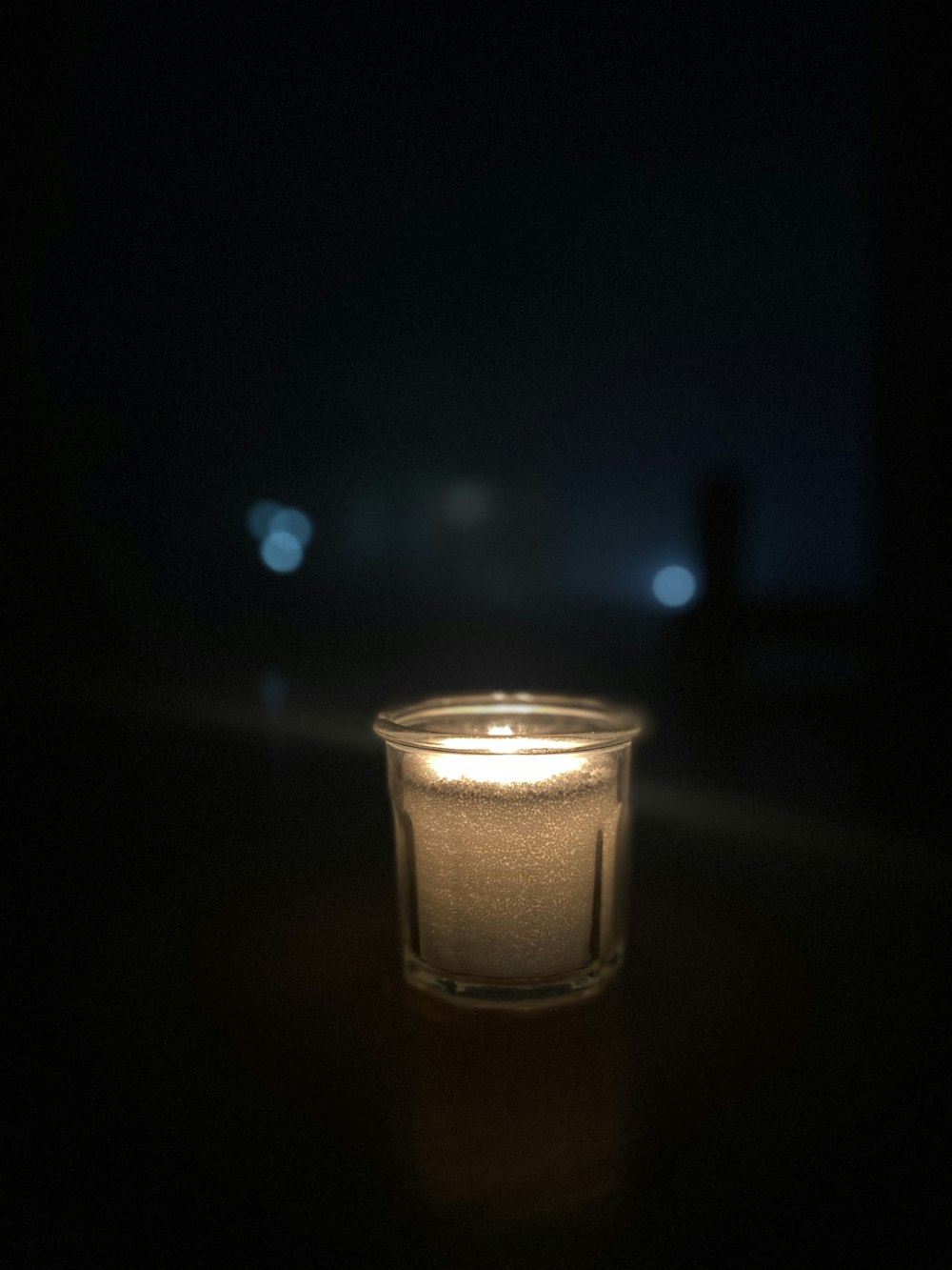 a lit candle sitting on a table in the dark