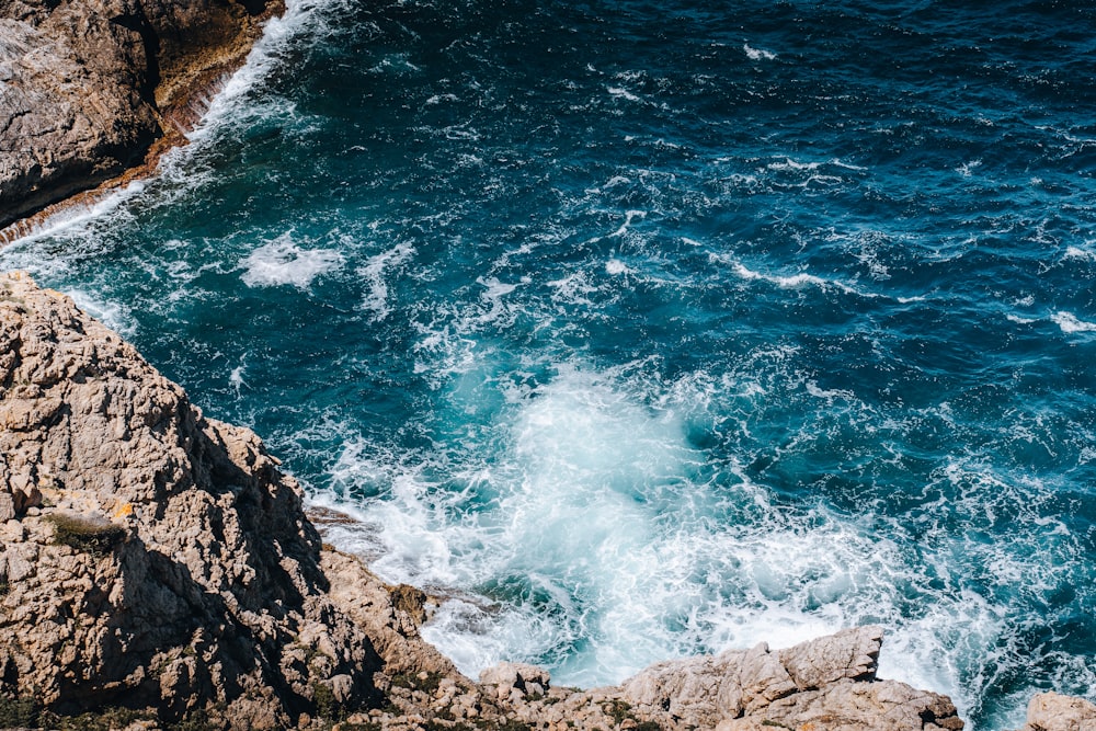 a man standing on top of a cliff next to the ocean