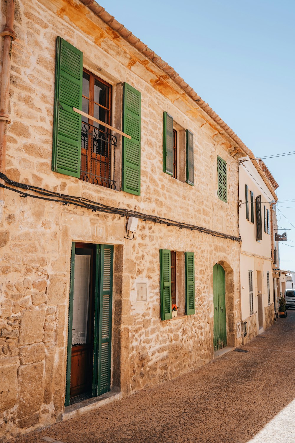 a stone building with green shutters and green shutters