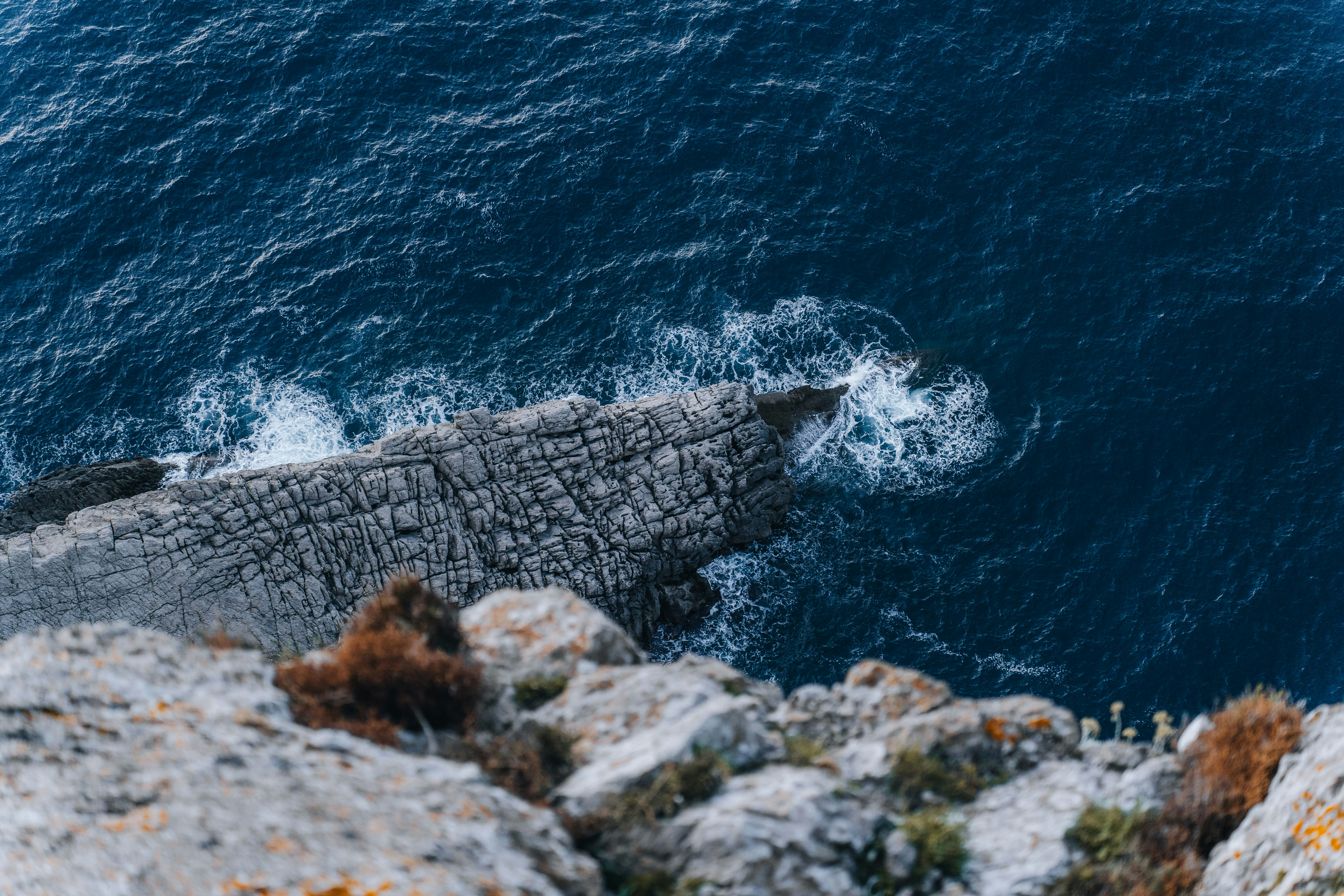 an aerial view of a rocky cliff with a body of water in the background