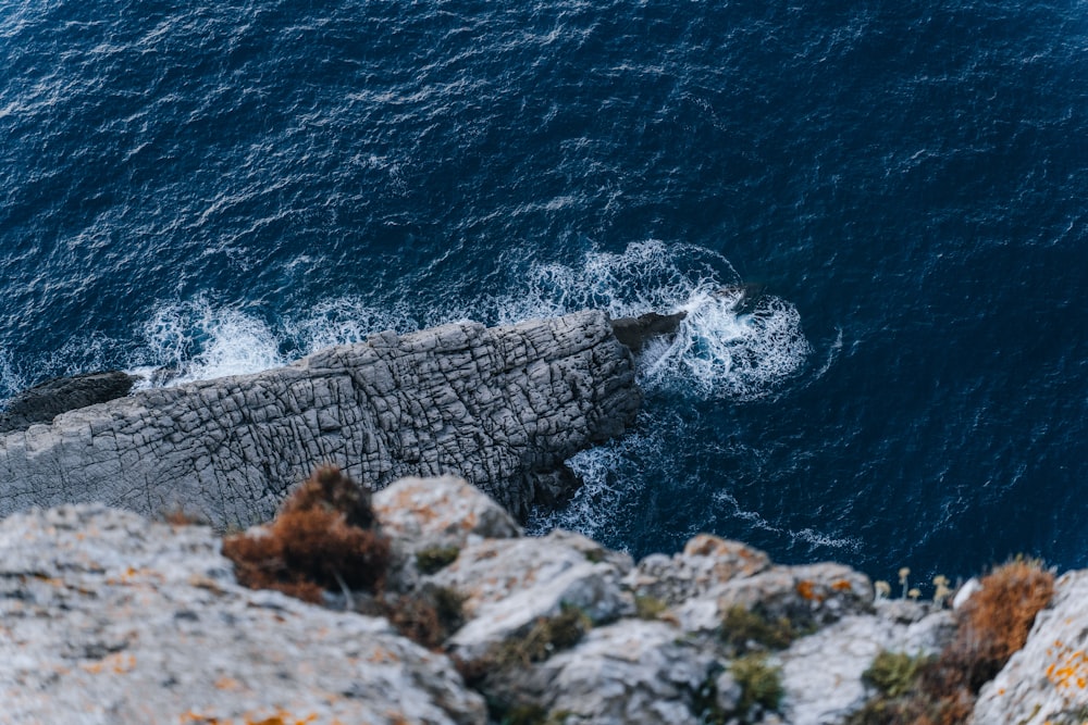 an aerial view of a rocky cliff with a body of water in the background