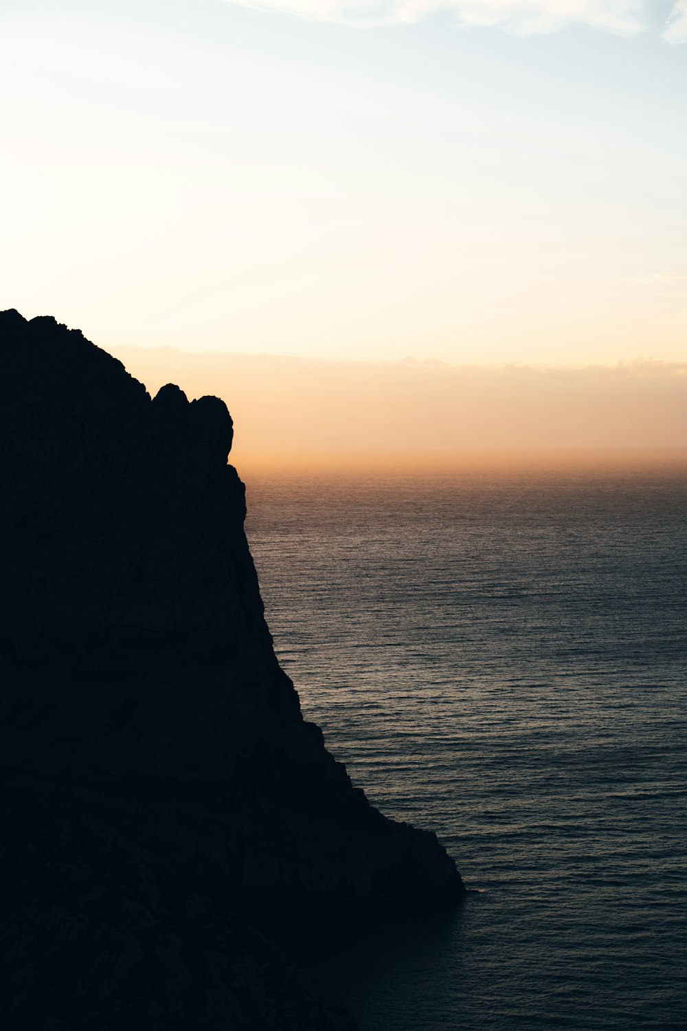 a person standing on top of a mountain next to the ocean