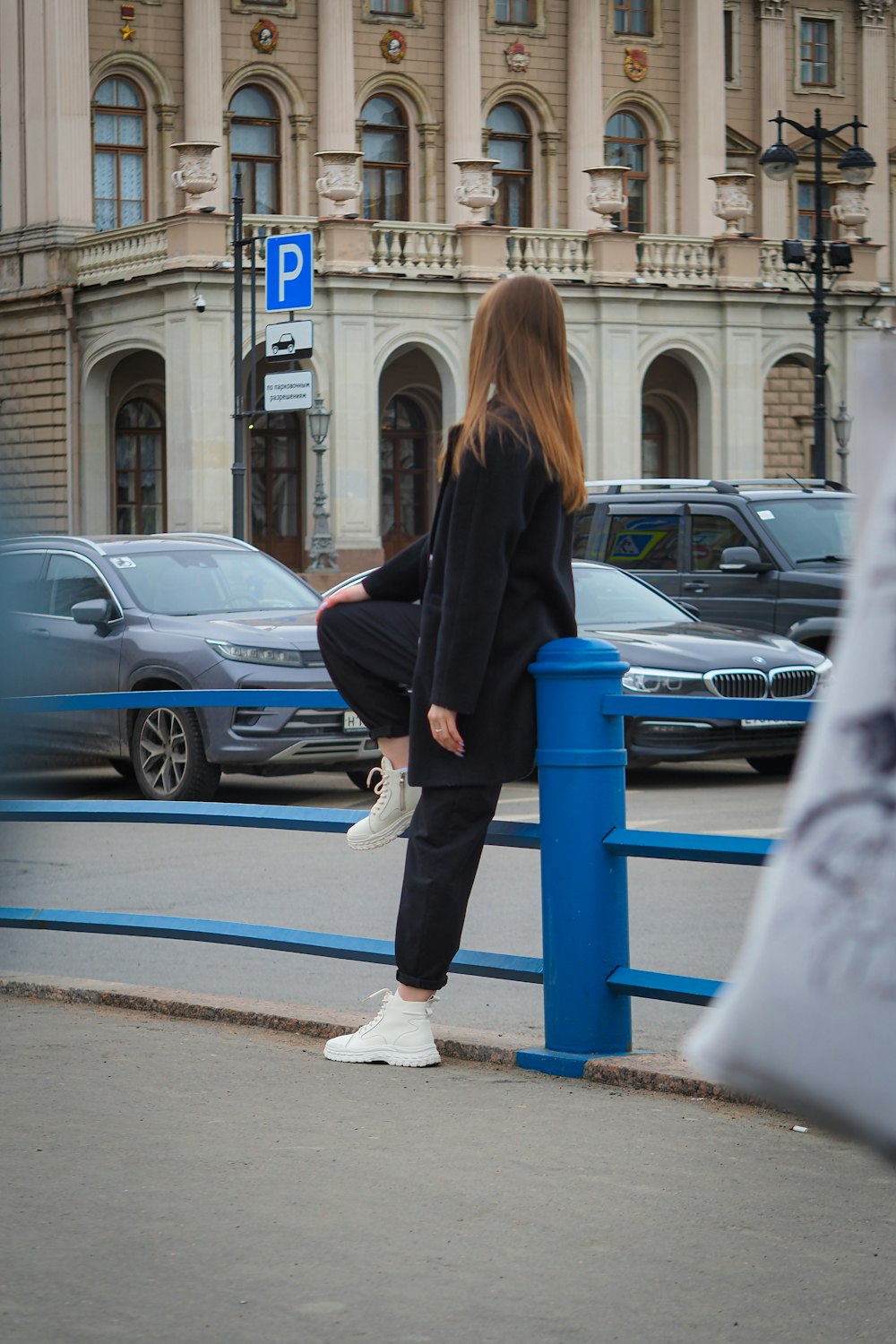 a woman sitting on a blue rail in front of a building