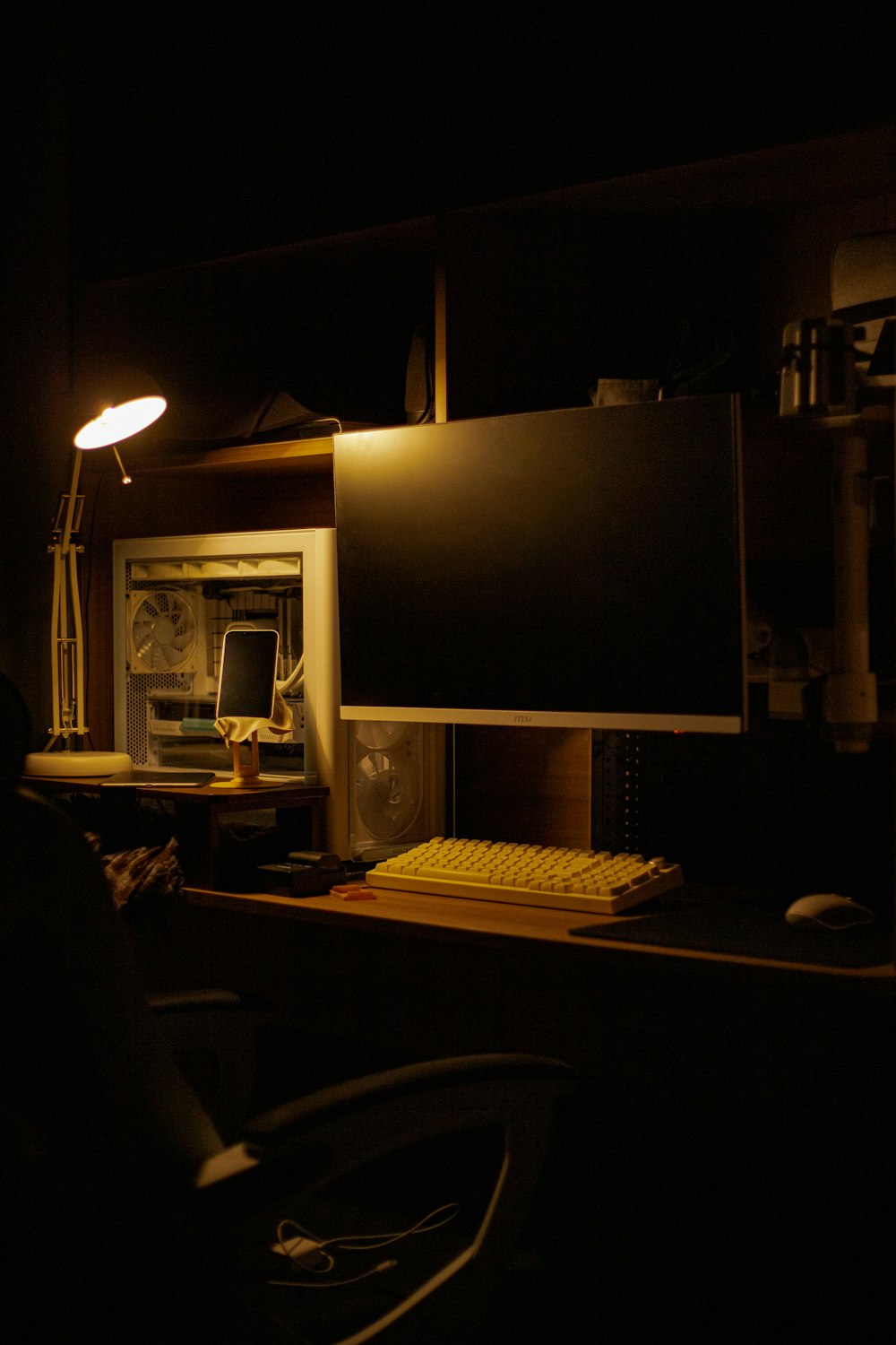 a computer desk with a monitor and keyboard in a dark room