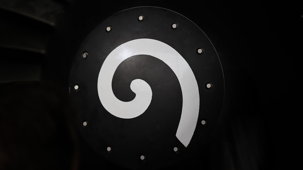 a black and white sign with a white swirl on it