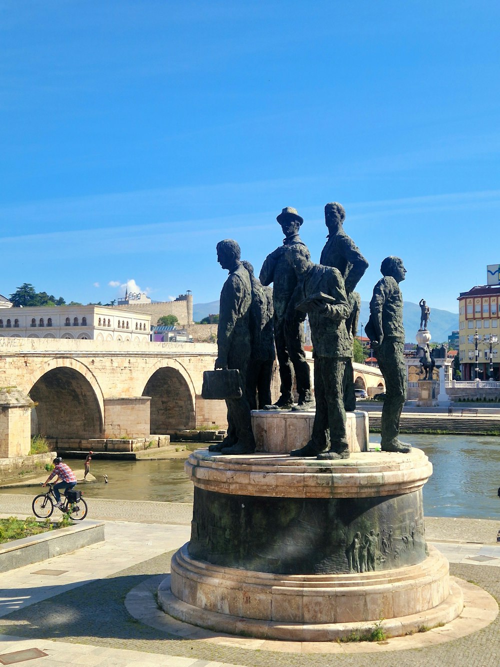 a statue of a group of people in front of a bridge