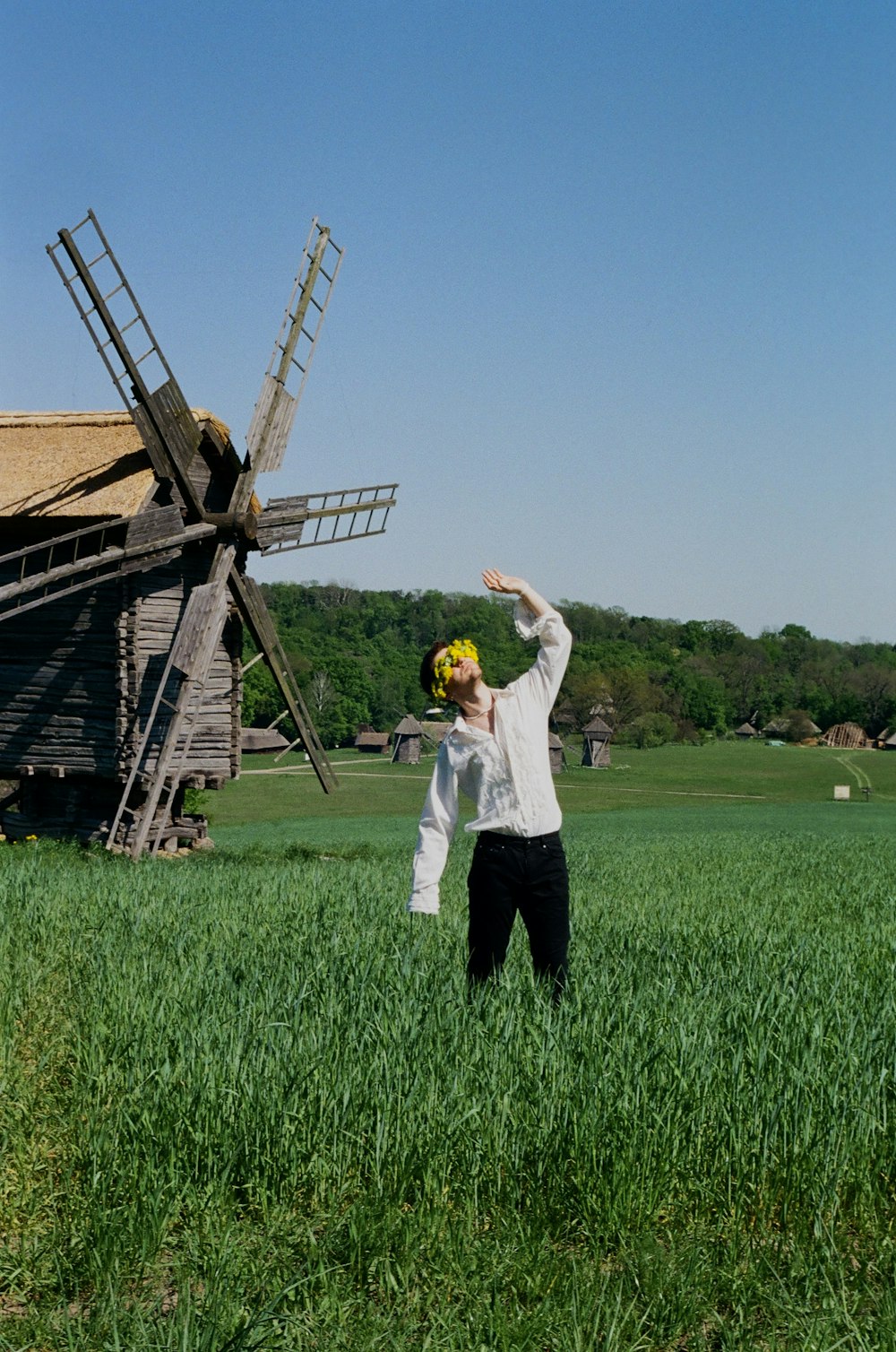 a person standing in a field with a windmill in the background