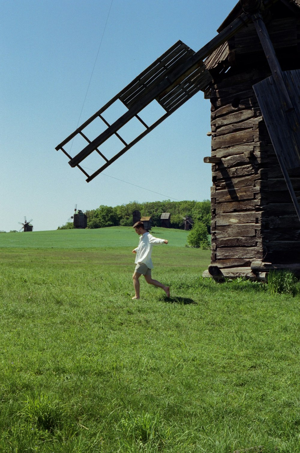 a young boy running through a field with a kite