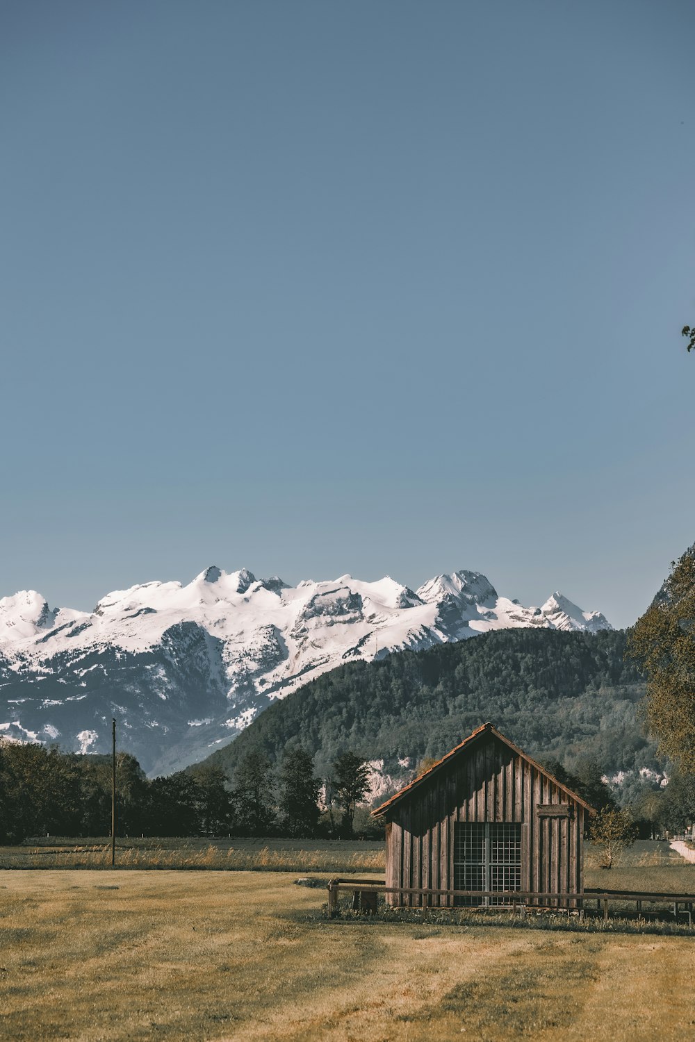 a cabin in a field with mountains in the background