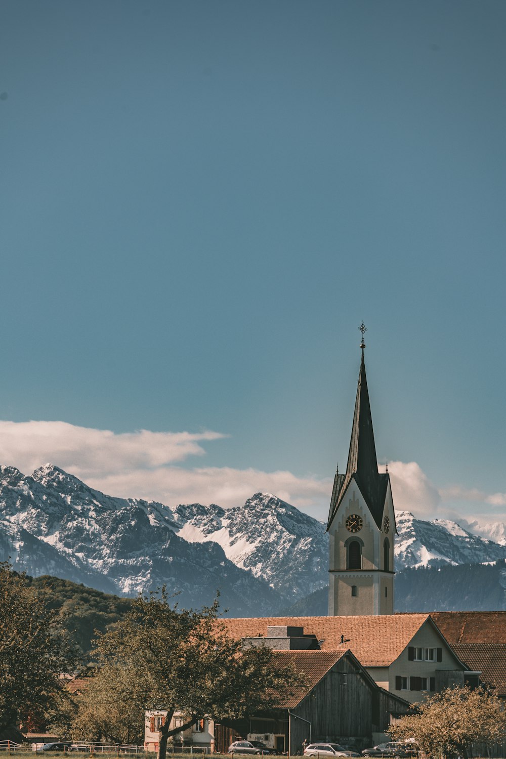 a church with a steeple in front of a mountain range