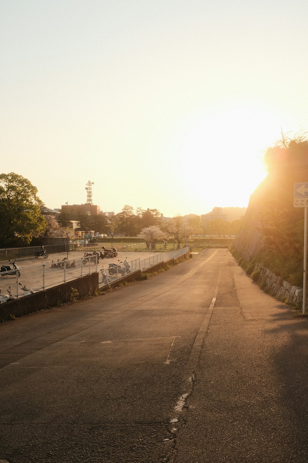 the sun is setting over a road with a street sign