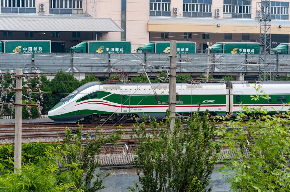 a green and white train traveling down train tracks