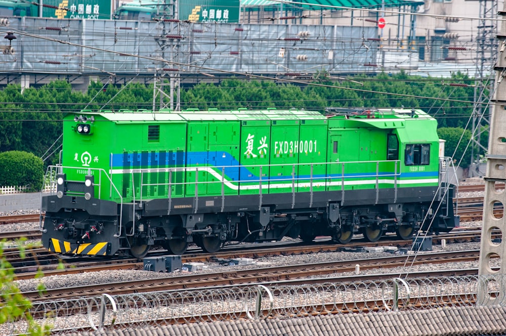 a green and blue train traveling down train tracks