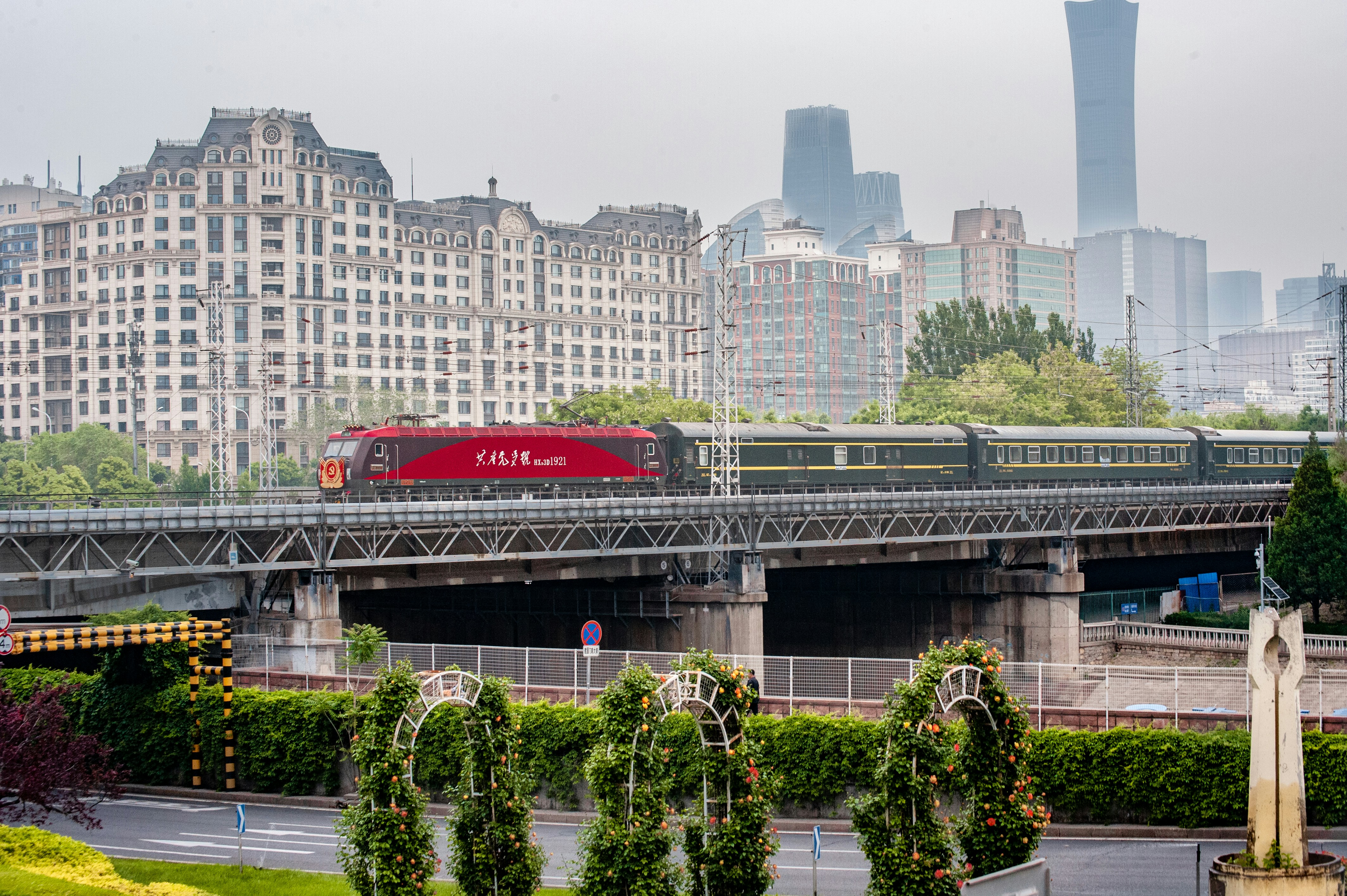 A red train traveling over a bridge next to tall buildings photo – Free ...