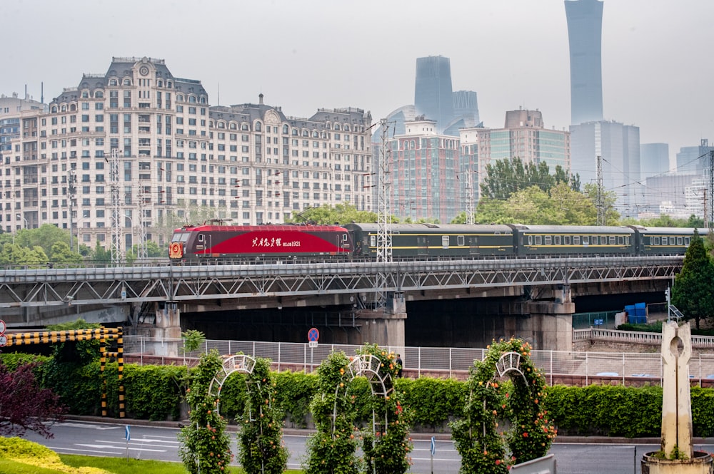 a red train traveling over a bridge next to tall buildings