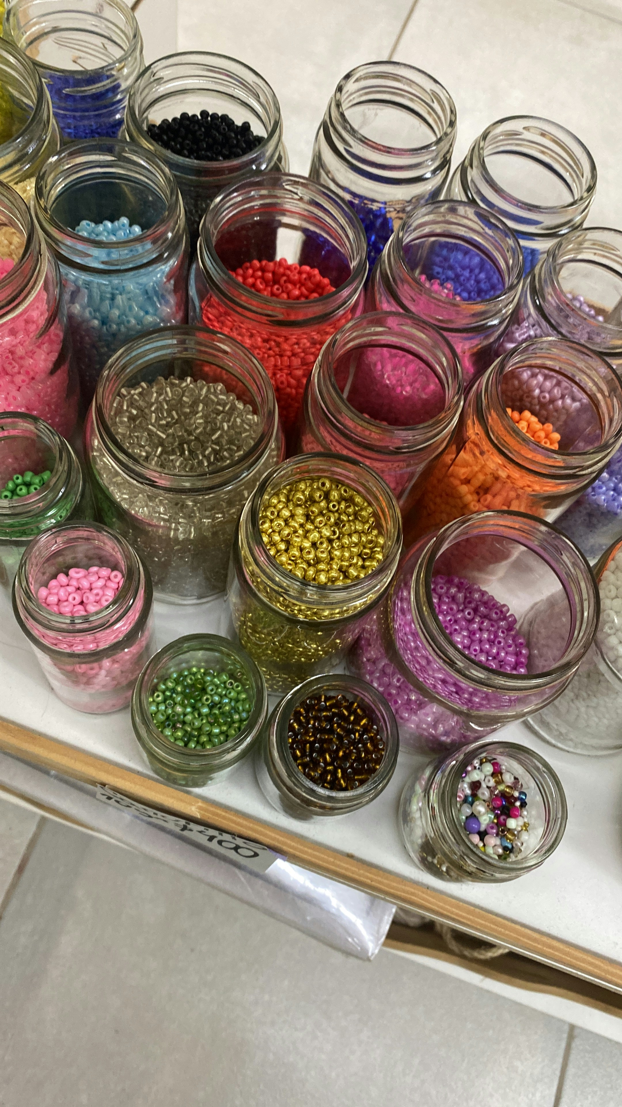 Colorful beads and craft materials arranged neatly on a white table in bright daylight