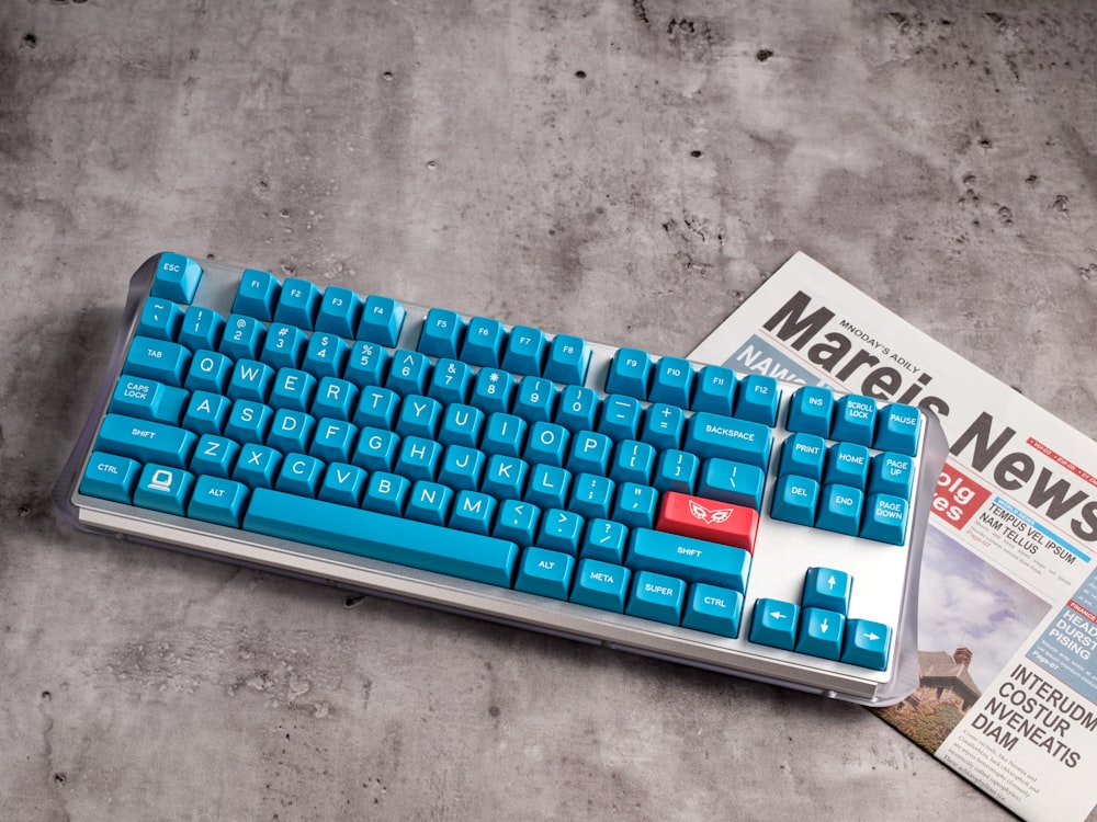 a blue keyboard sitting on top of a magazine