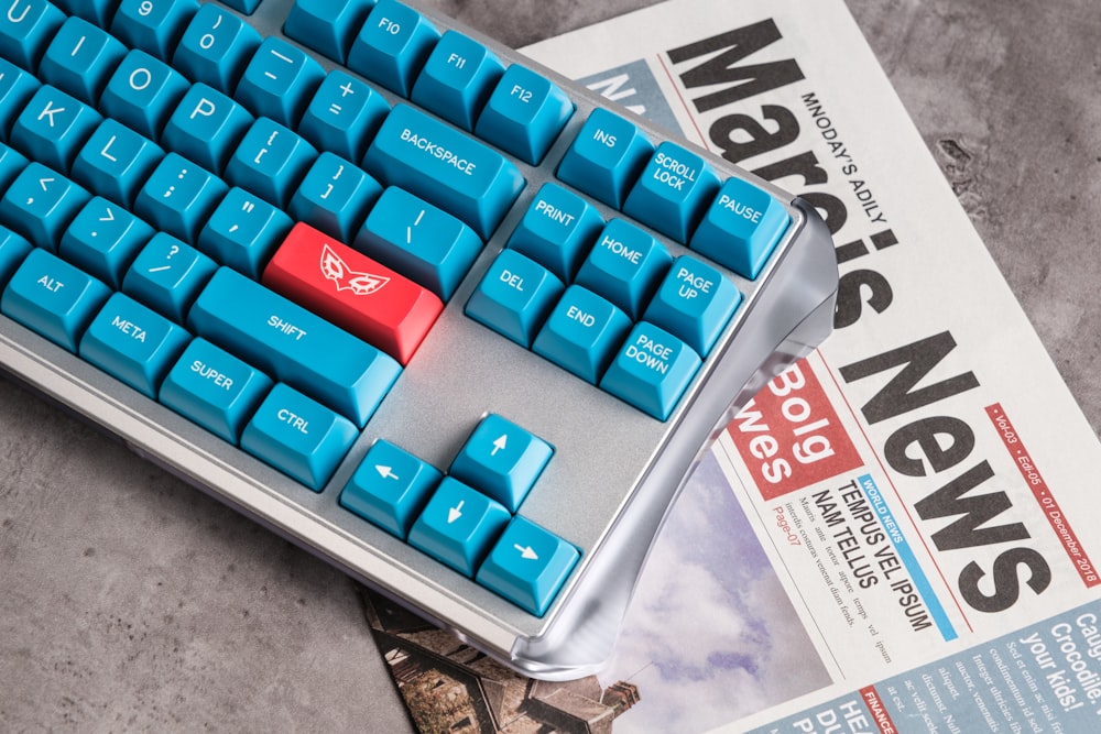a blue keyboard sitting on top of a newspaper