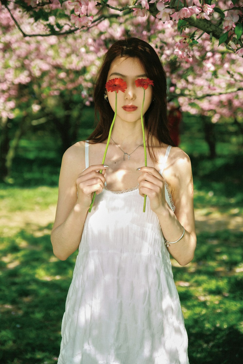 a woman in a white dress holding a flower in front of her face