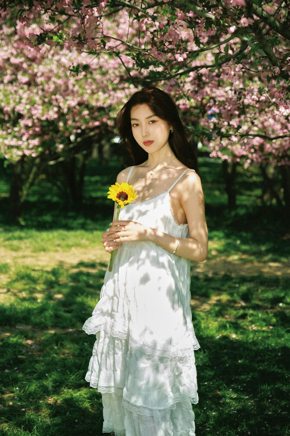 a woman in a white dress holding a sunflower