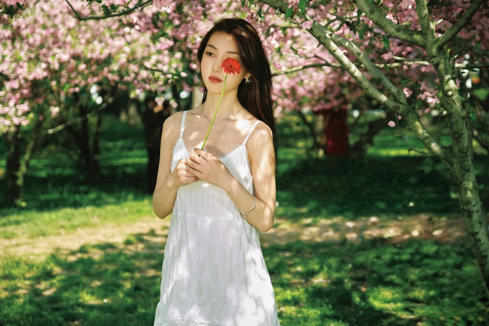 a woman in a white dress holding a flower