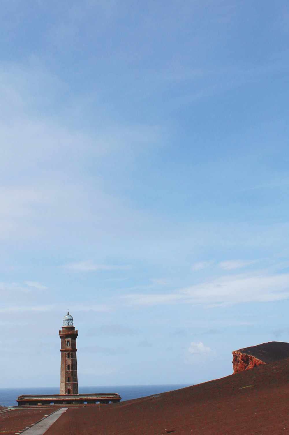 a lighthouse on top of a hill near the ocean