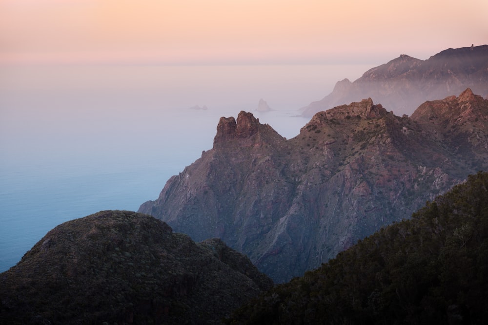 a view of a mountain range with fog in the air