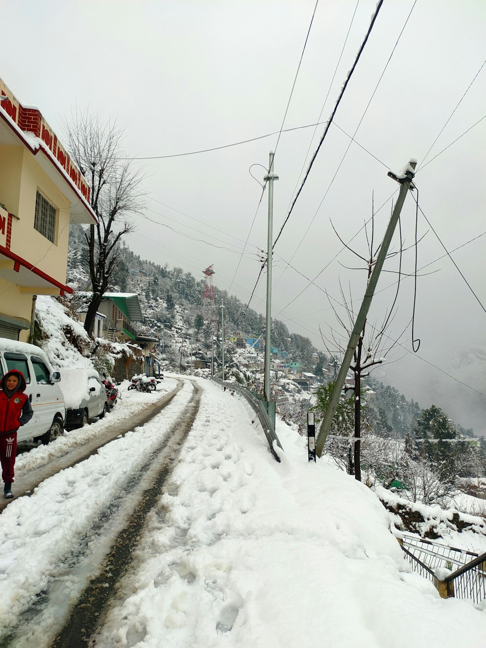 a snow covered street with cars parked on the side