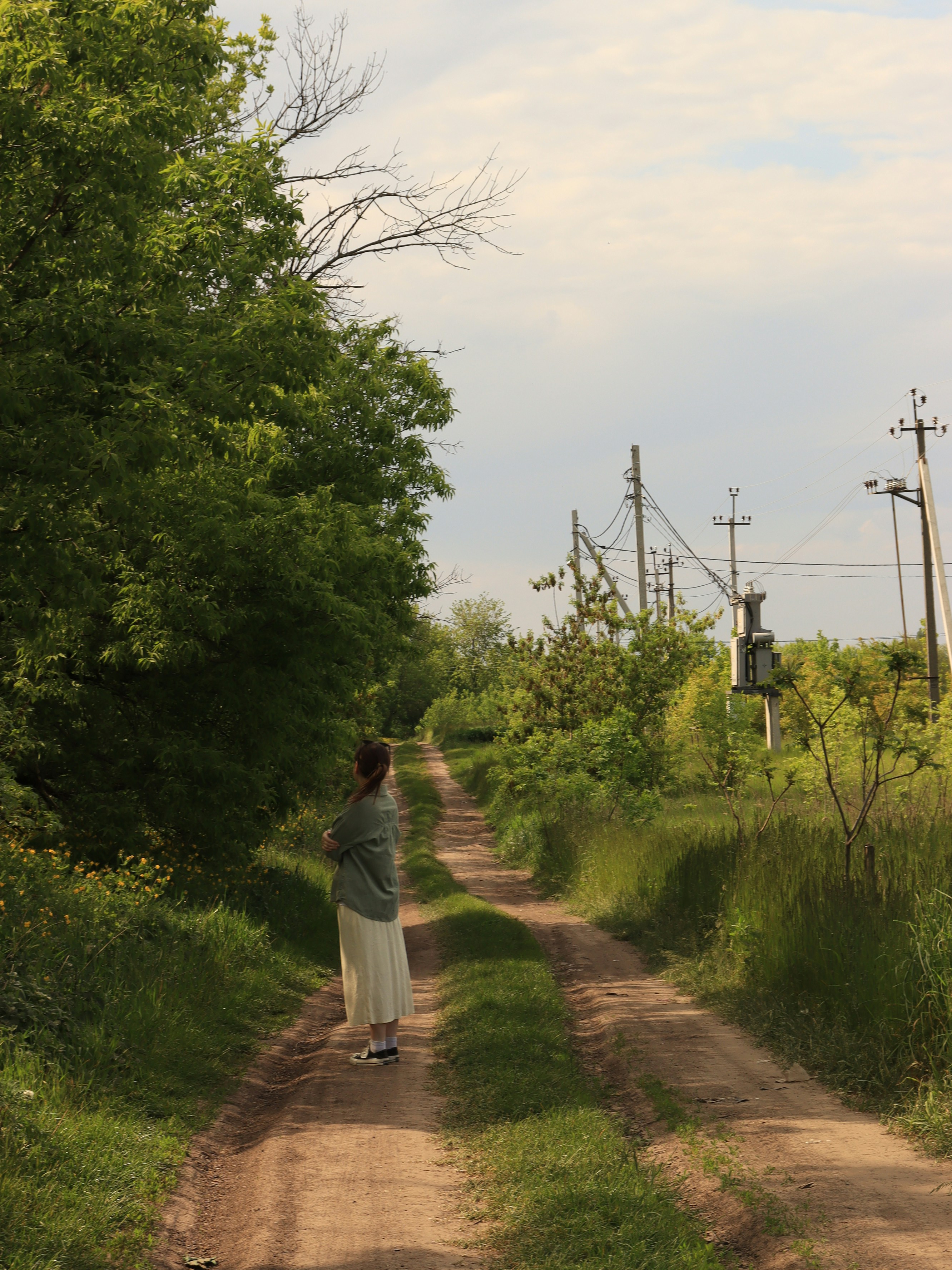 a woman is walking down a dirt road