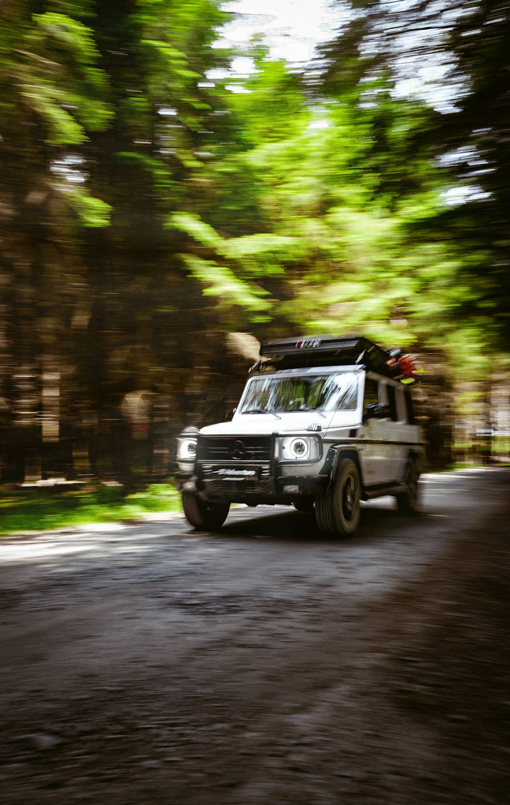 a white truck driving down a road next to a forest