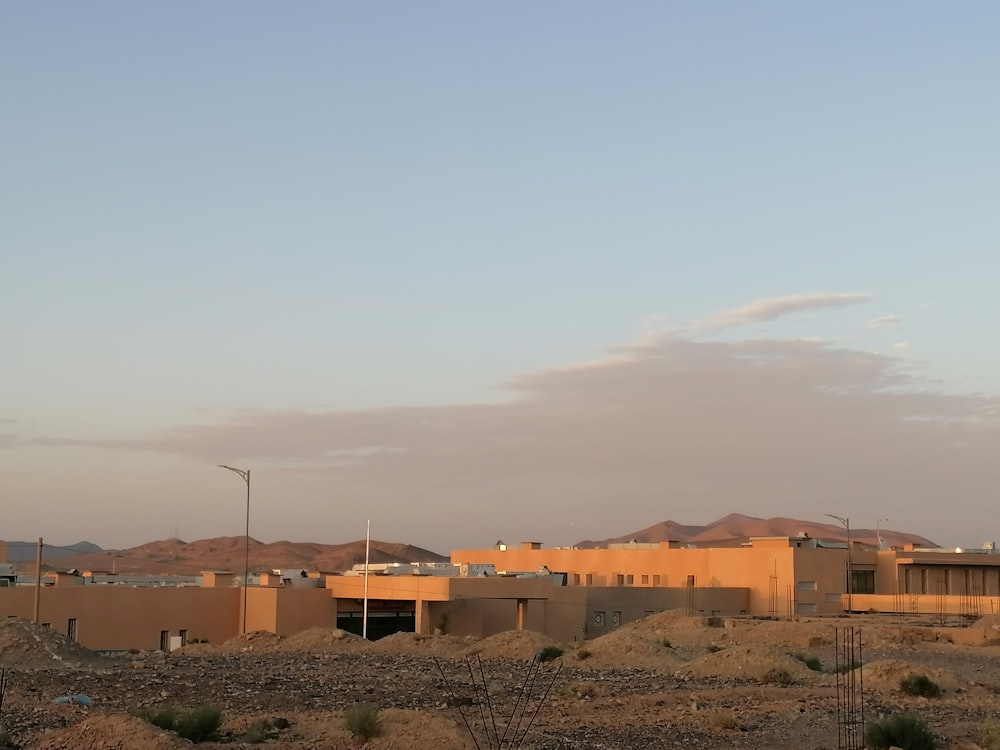 a desert scene with a building and mountains in the background