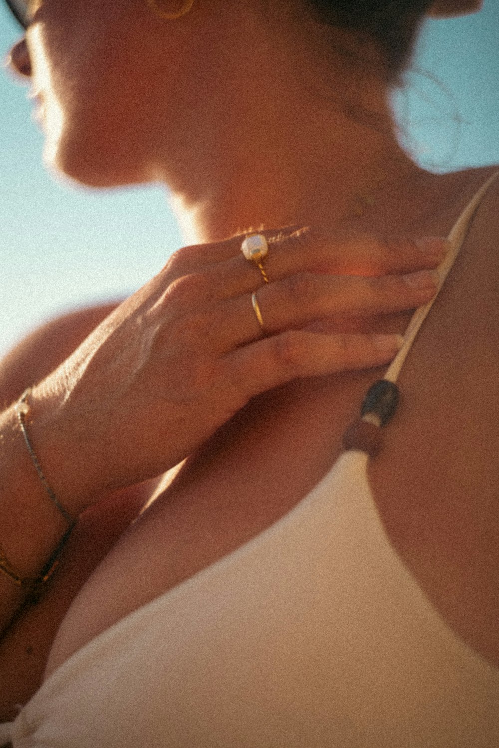 a woman wearing a white tank top and gold rings