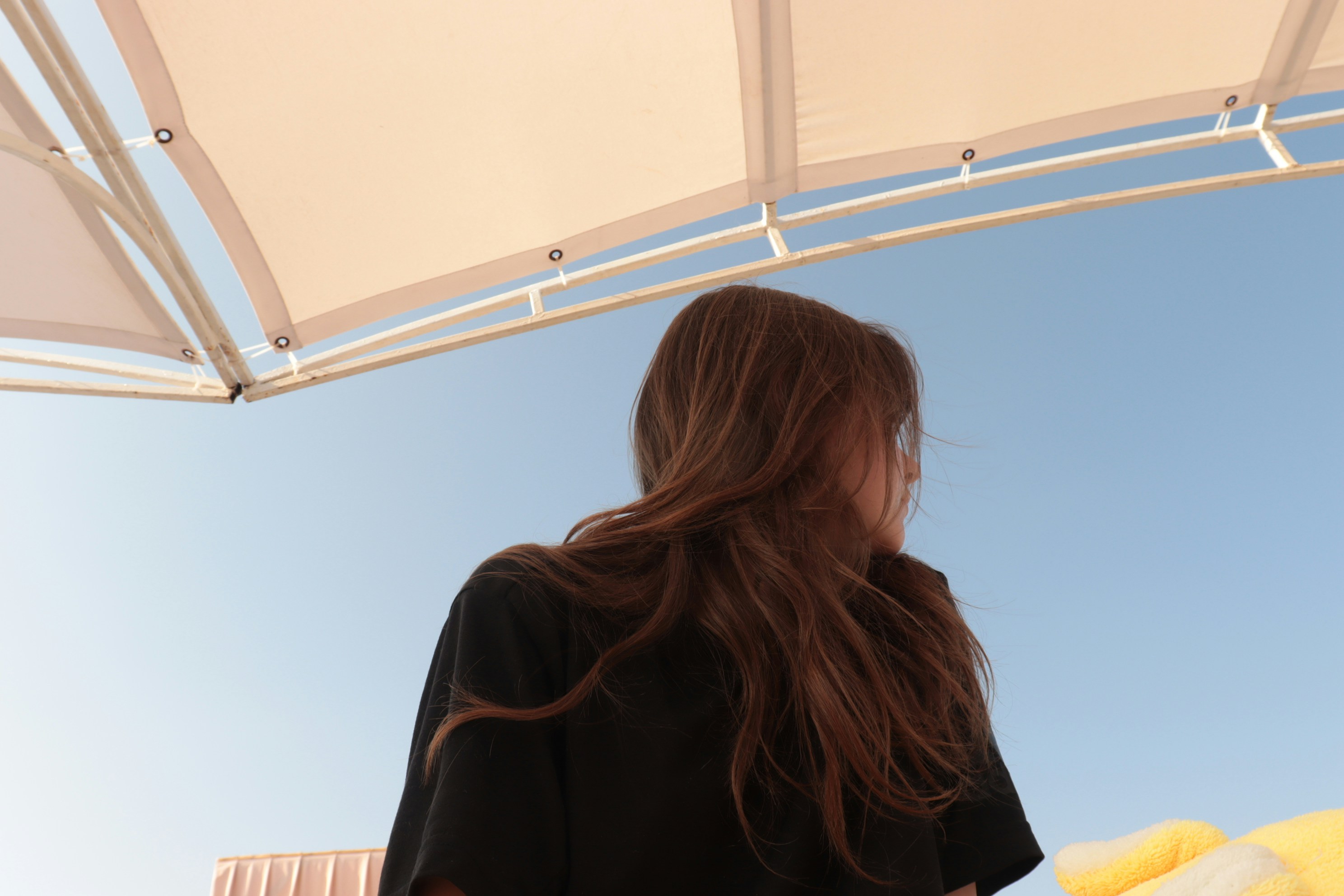 a woman standing under a white umbrella under a blue sky