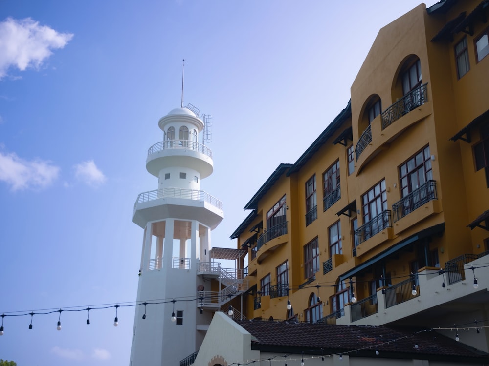 a tall white tower sitting next to a yellow building