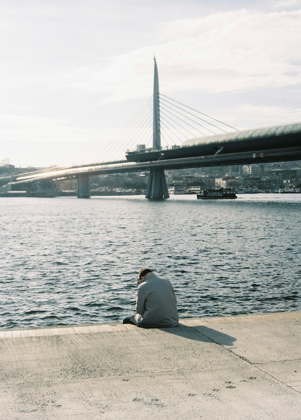 a man sitting on the ground next to a body of water