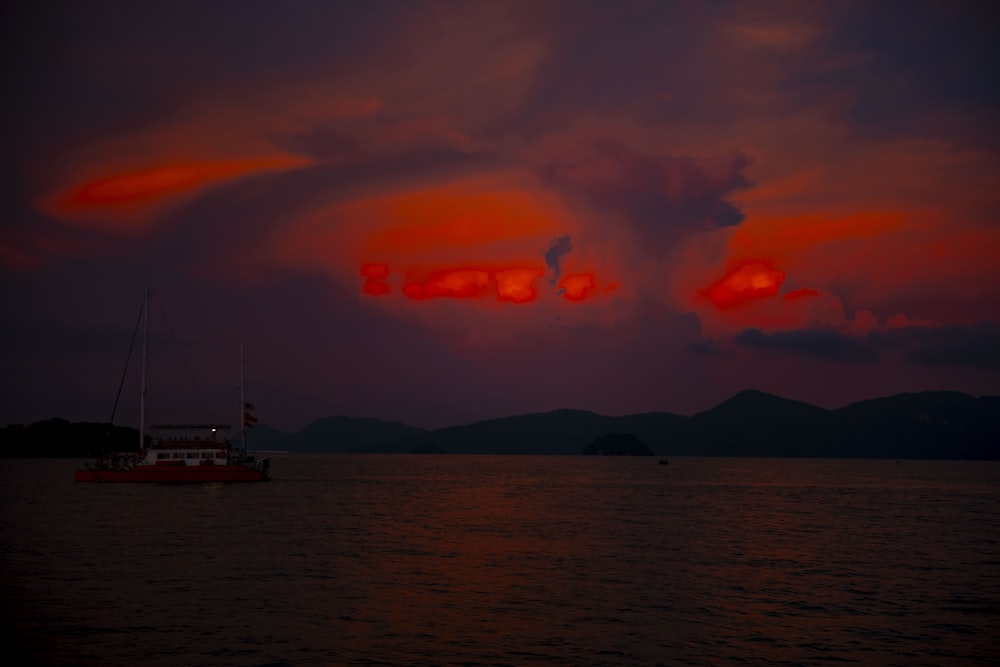 a boat floating on top of a body of water under a cloudy sky