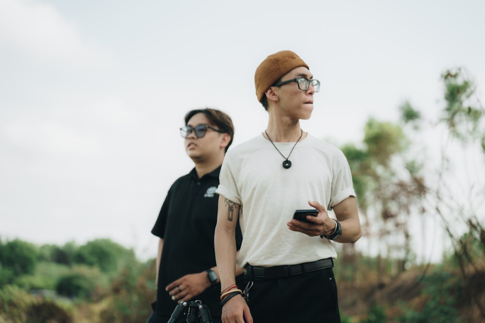 two men standing next to each other holding cell phones