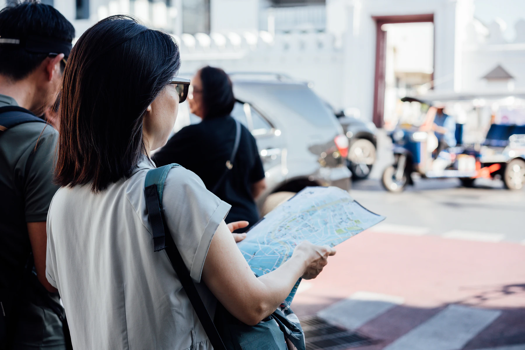 Two travellers hold a folded street map while standing near a busy road.