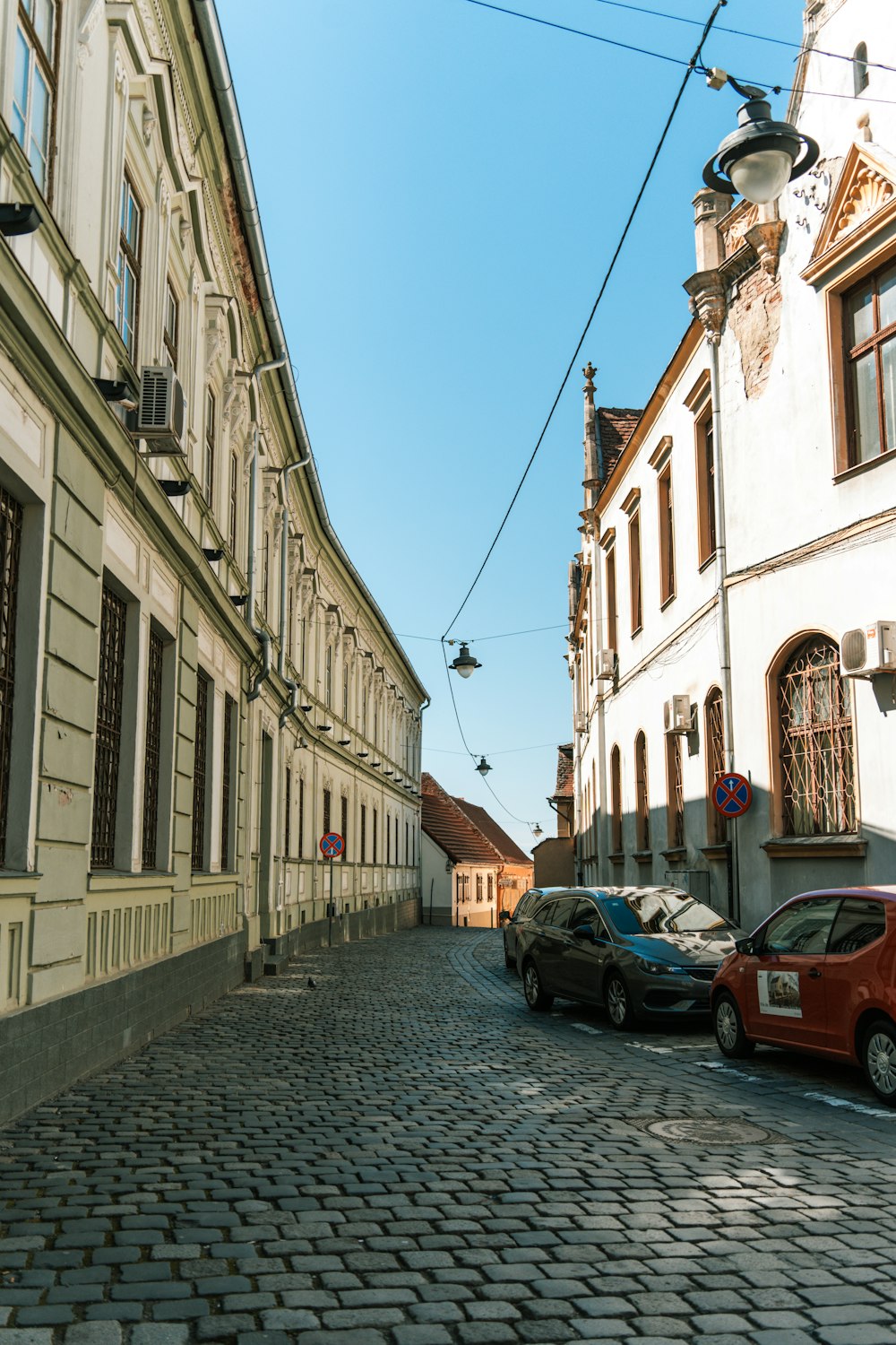 a cobblestone street lined with parked cars