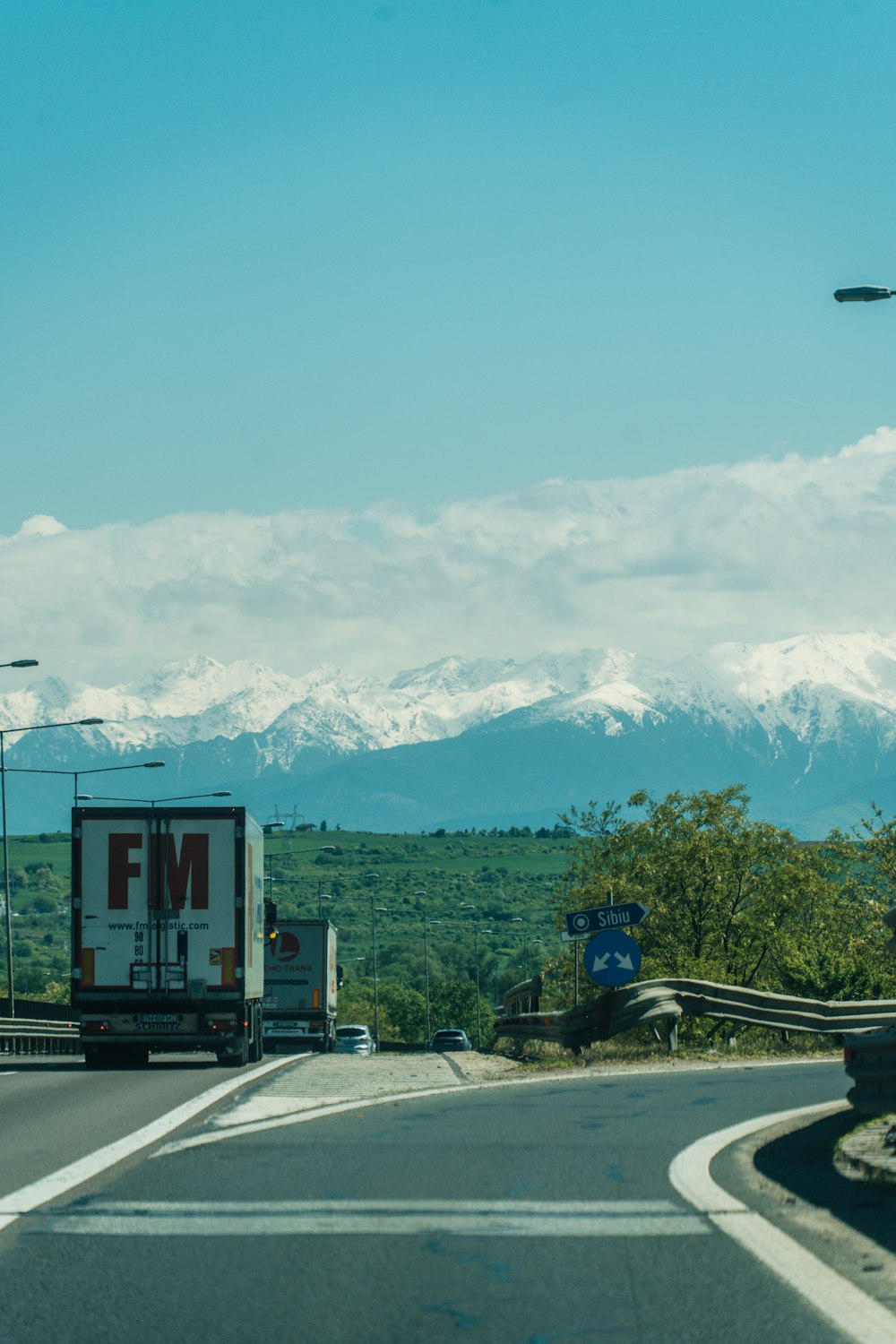 a truck driving down a road with mountains in the background