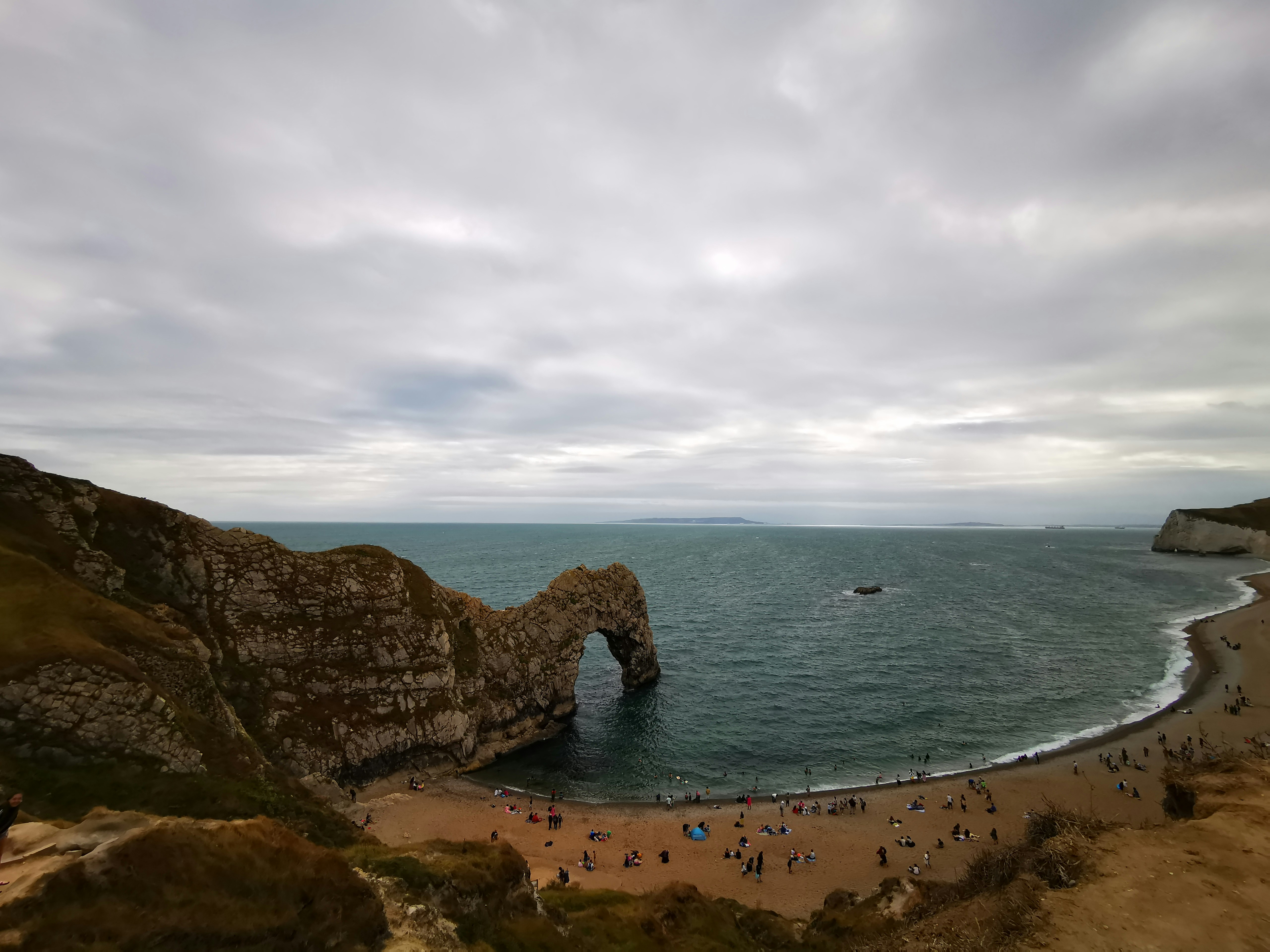 a group of people standing on top of a beach next to the ocean