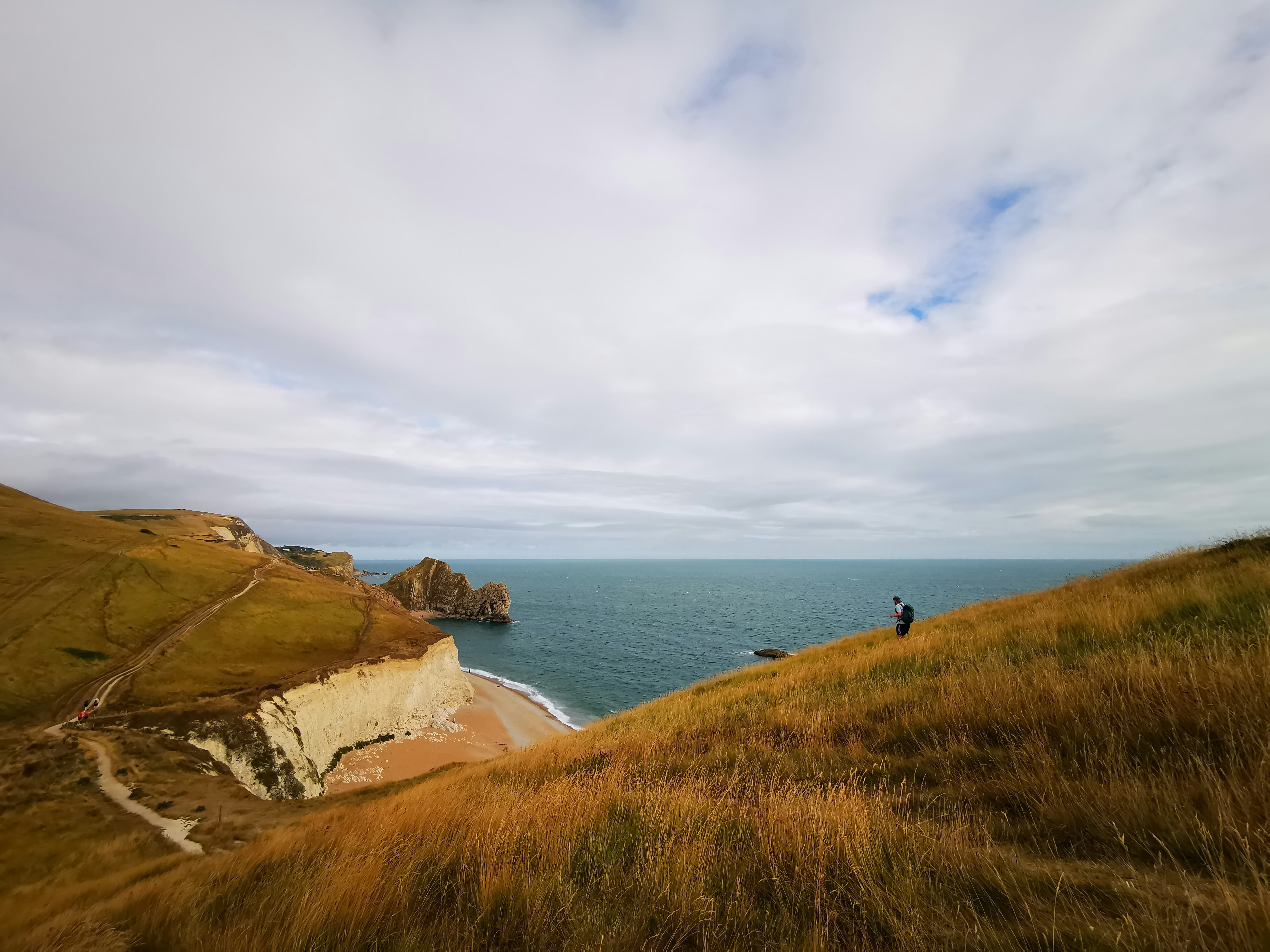 a person standing on top of a hill near the ocean, Coastline trails in England