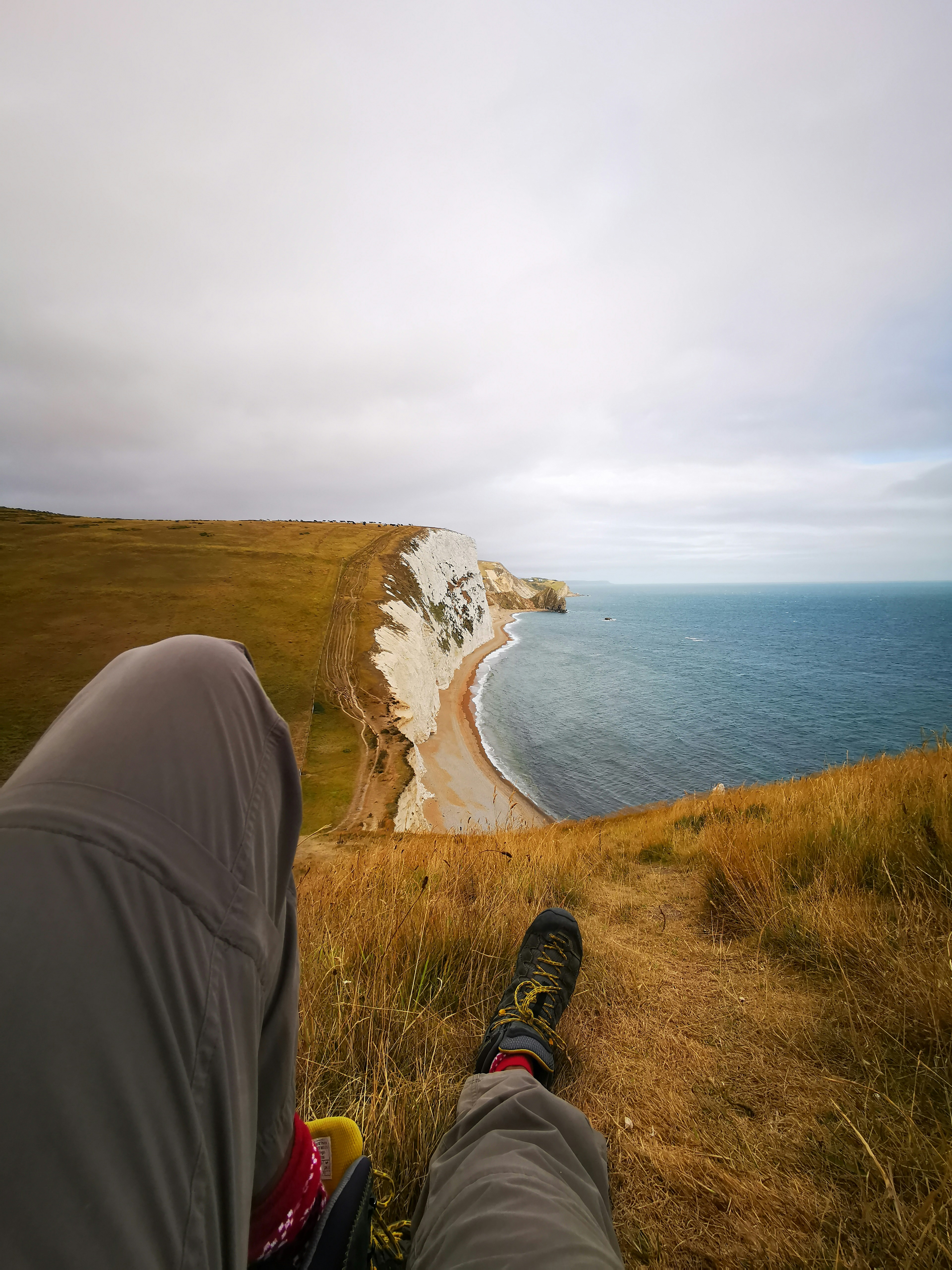 a person sitting on top of a hill next to the ocean
