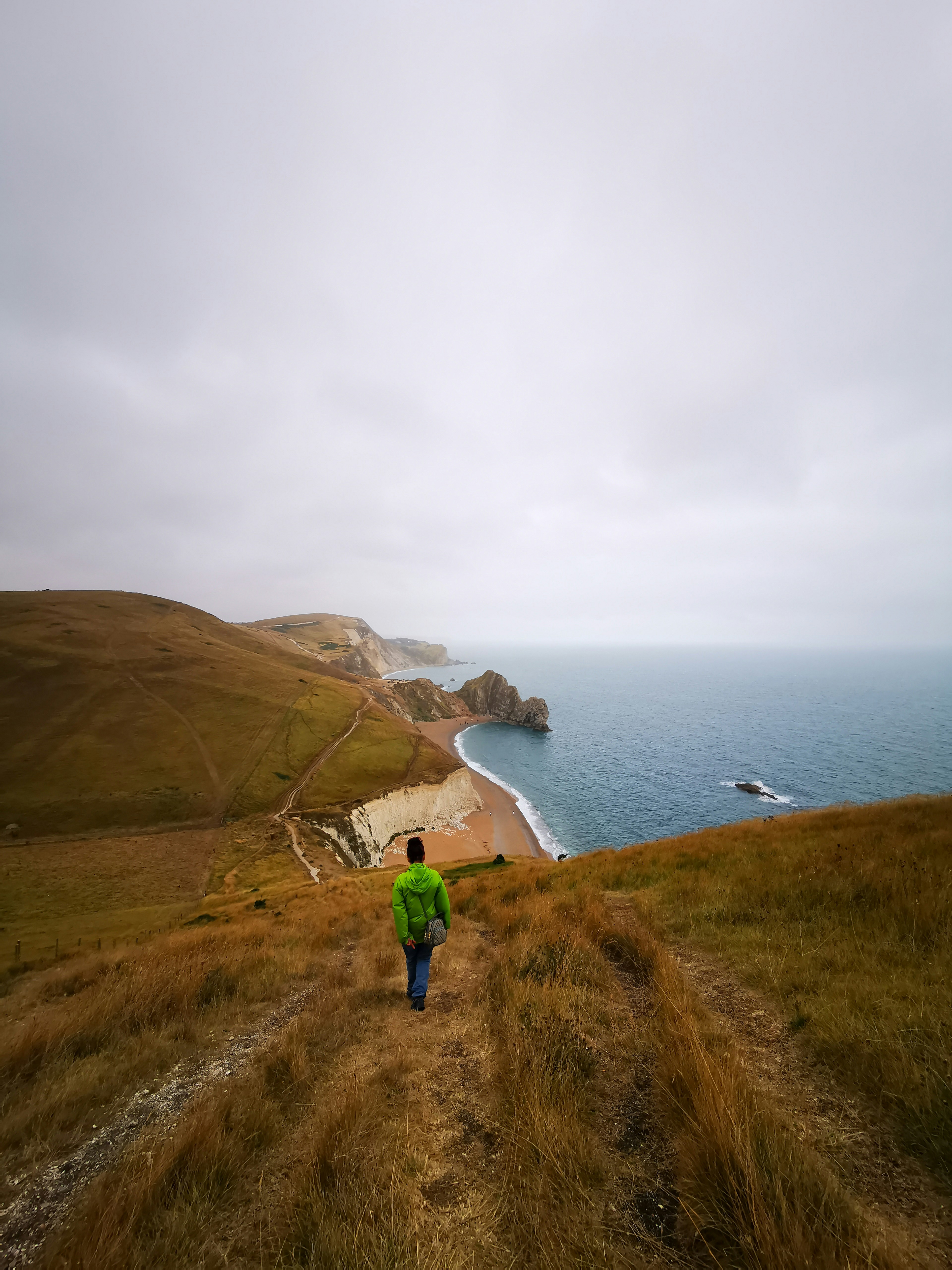 a person in a green jacket walking down a hill