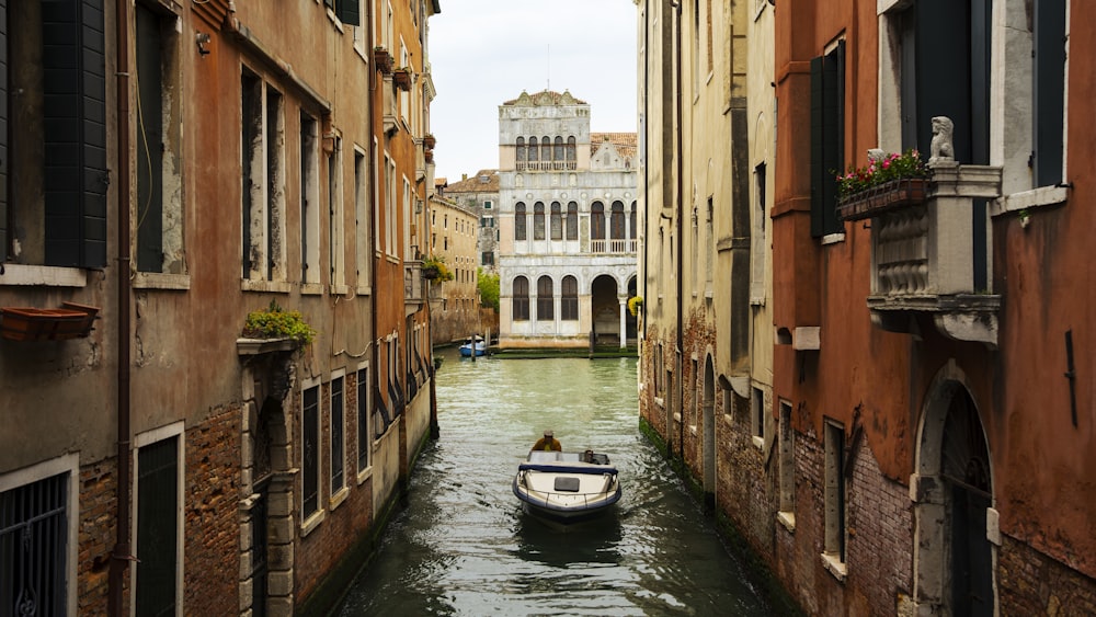 a small boat floating down a narrow canal between two buildings