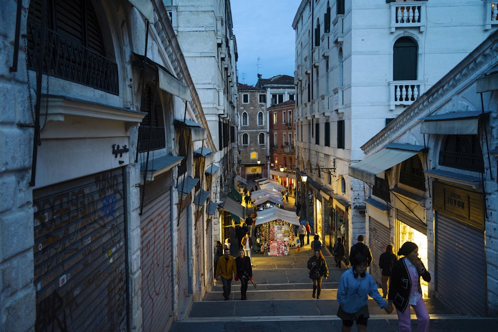 a group of people walking down a street next to tall buildings