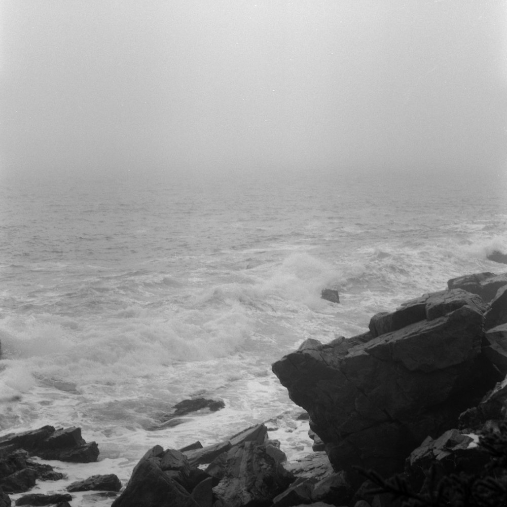 a black and white photo of the ocean and rocks