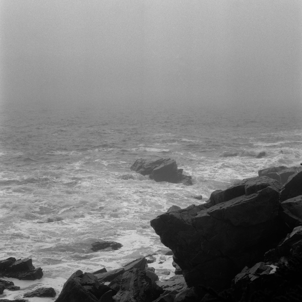a black and white photo of the ocean on a foggy day
